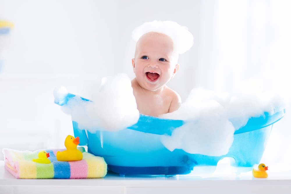 Iloinen naurava vauva käy kylvyssä leikkimällä vaahtokupla